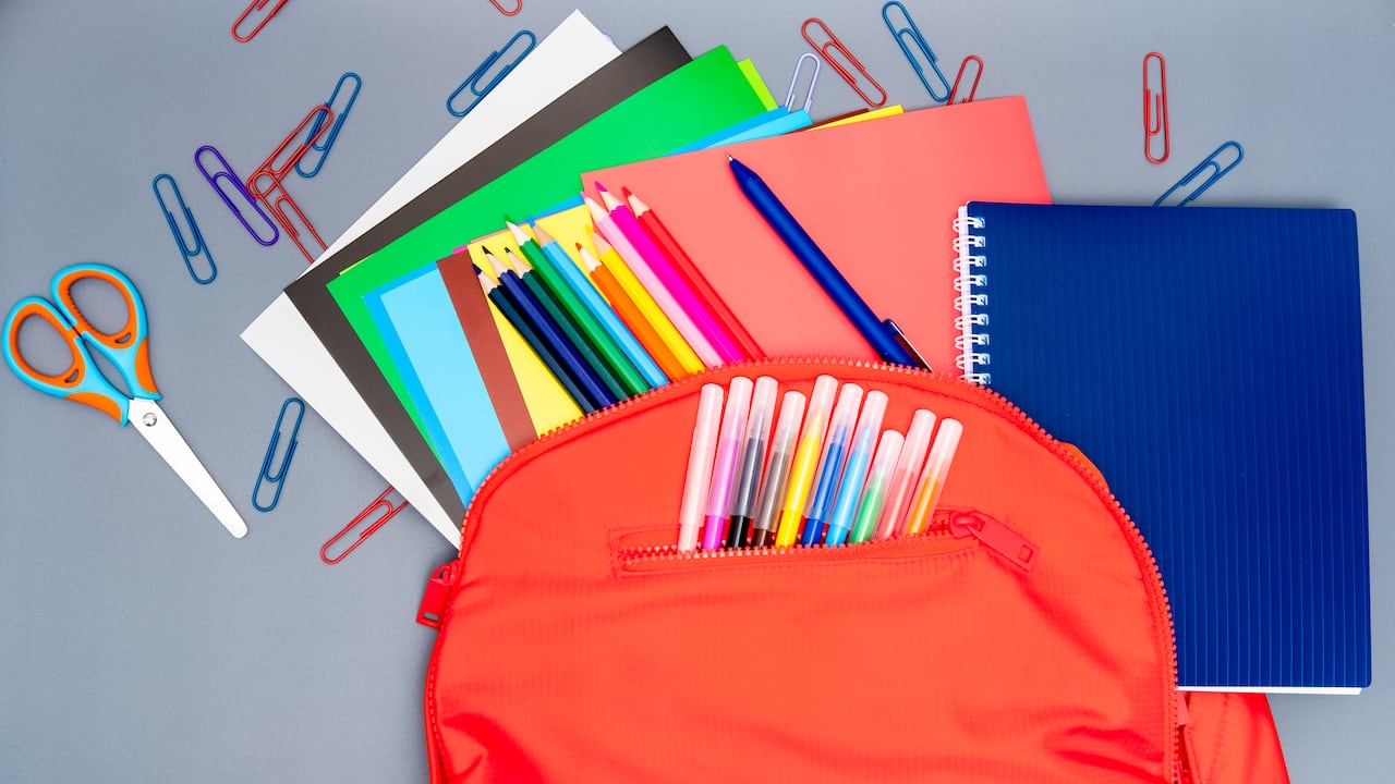 Ápices de colores, clips y cuadernos sobre fondo gris.