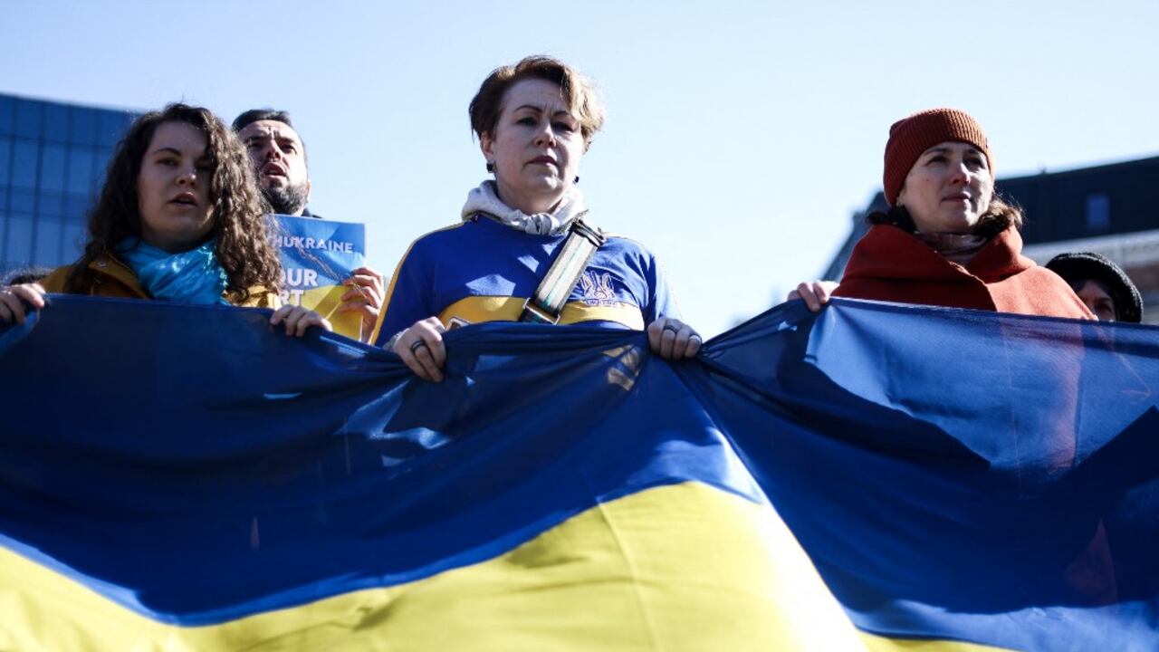 Las mujeres sostienen una bandera ucraniana cerca de las instituciones europeas durante una manifestación llamada "Las mujeres están con Ucrania" contra la operación militar de Rusia en Ucrania como parte del Día Internacional de la Mujer en Bruselas, el 8 de marzo de 2022.
Kenzo TRIBOUILLARD / AFP