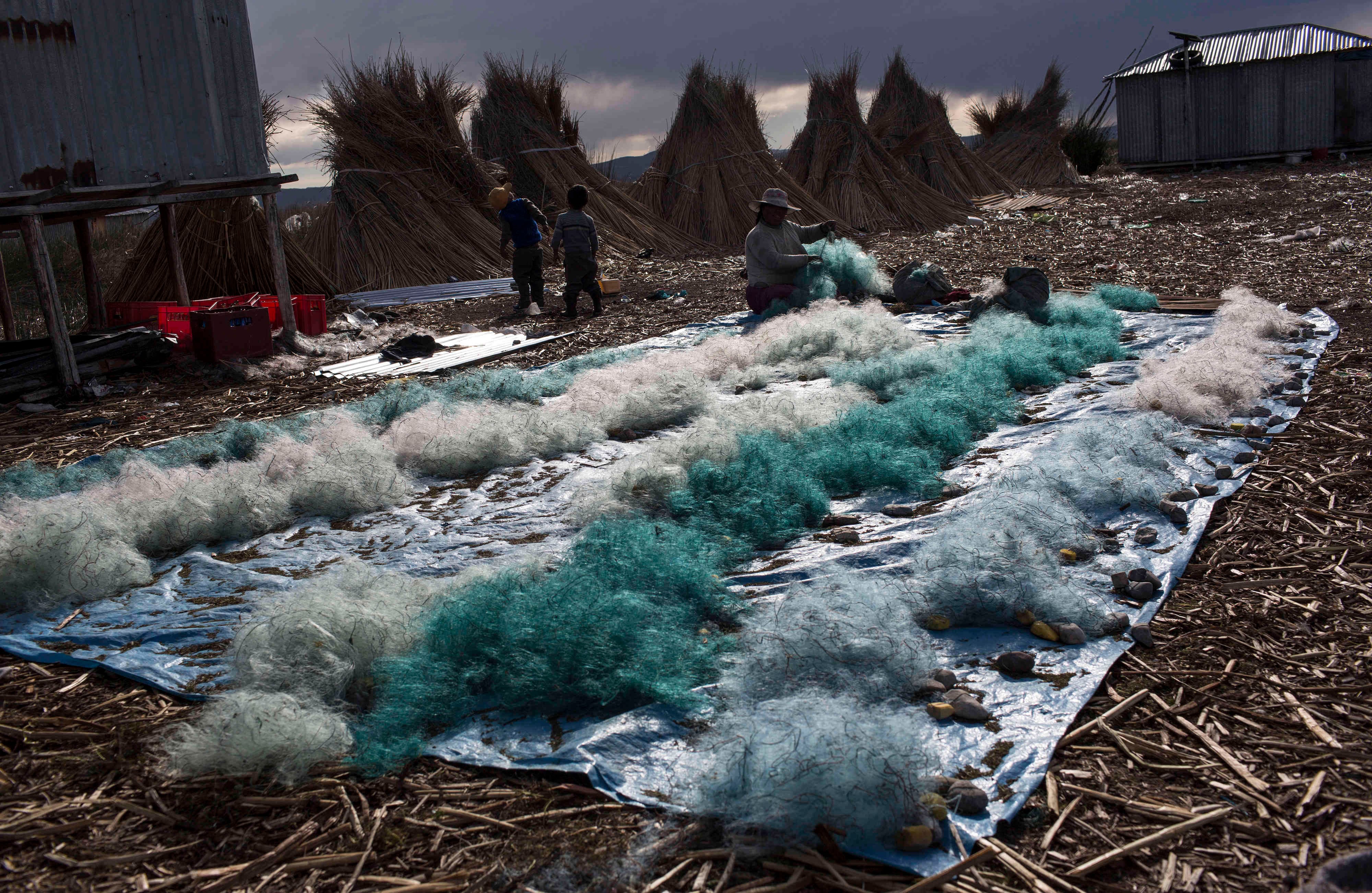 En esta foto del 4 de febrero de 2017, Naty Lugano Quispe limpia las redes de pesca en Kapi Cruz Grande, una aldea a orillas del lago Titicaca, Perú. Un estudio de 2014 sugirió que los funcionarios limitan el consumo de pescado, pero los habitantes de la zona dijeron que no fueron informados sobre el estudio (AP Photo / Rodrigo Abd)