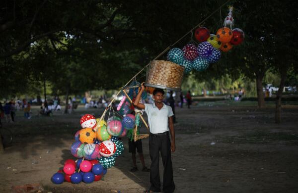 Un vendedor espera a sus clientes en las sombras de los árboles, durante una soleada tarde en Nueva Delhi, India. (AP)