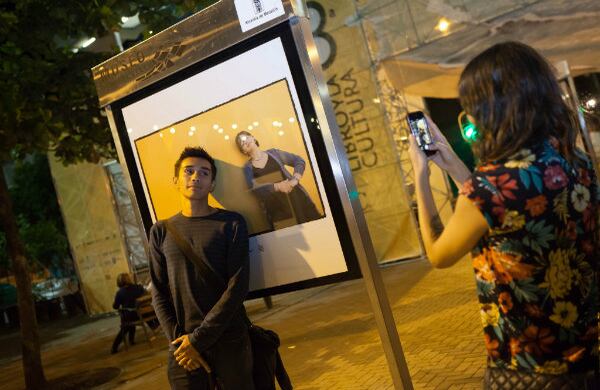 Un transeúnte posa junto a una foto de Piedad Bonnett, en la exposición al aire libre 34+2, del fotógrafo argentino Daniel Mordzinski.
