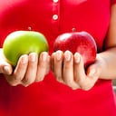 Asian woman holds a red delicious apple and a green granny smith apple
