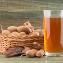 Jugo de tamarindo en un vaso rodeado de tamarindos maduros frescos - Tamarindus indica