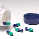 Frasco de pastillas abierto con pastillas derramándose