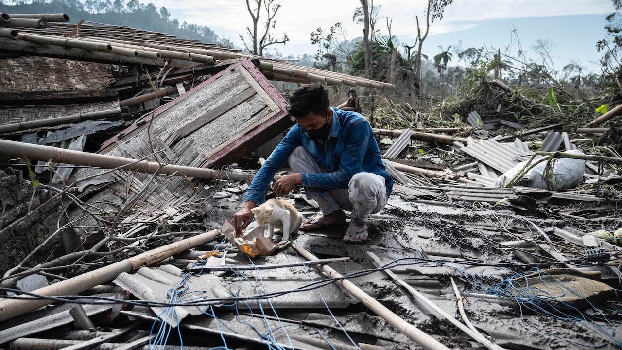 Un aldeano rescata sus pertenencias de su casa dañada en la aldea de Curah Kobokan en Lumajang el 8 de diciembre de 2021, después de la erupción del volcán Monte Semeru. (Foto por Juni Kriswanto / AFP)