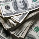 Pila de billetes de cien dólares sobre fondo de dólares