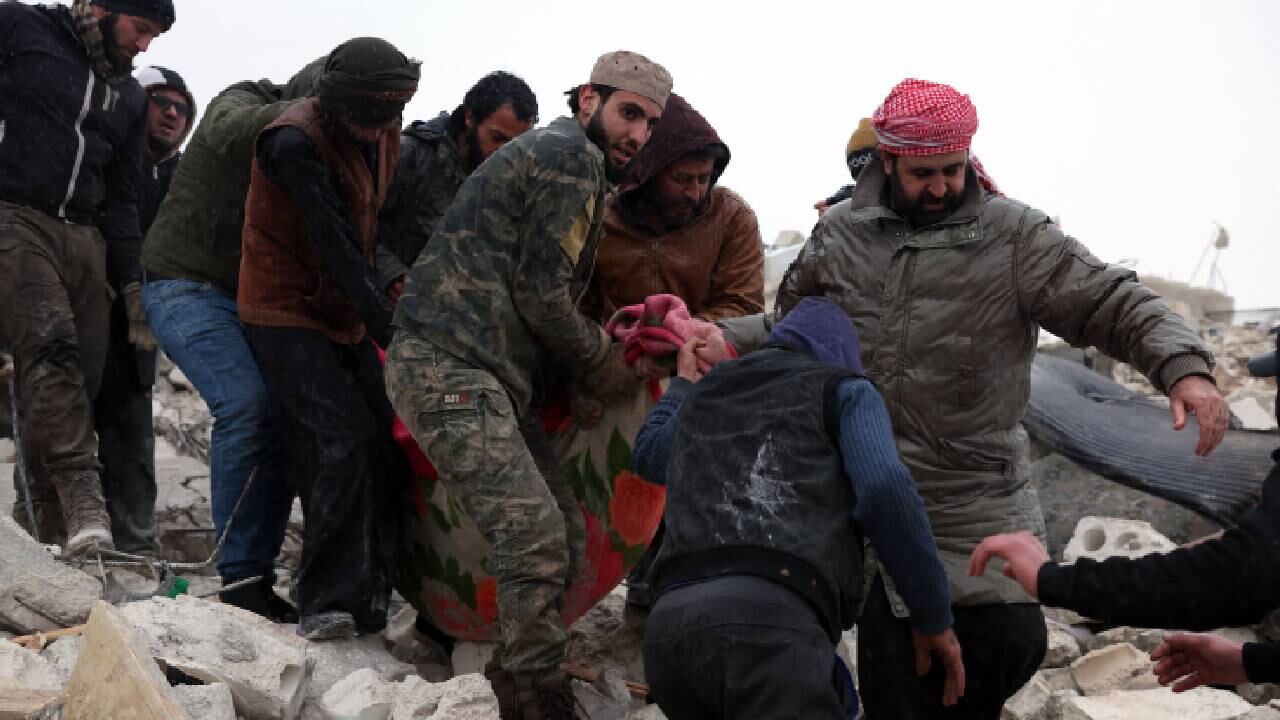 Residentes y rescatistas recuperan a una víctima de los escombros de un edificio derrumbado luego de un terremoto en la aldea de Besnaya en la provincia de Idlib, en el noroeste de Siria.