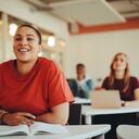 Estudiante que se sienta en el aula de la universidad y la sonrisa. Mujer prestando atención en la clase.