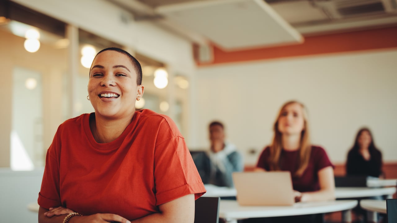 Estudiante que se sienta en el aula de la universidad y la sonrisa. Mujer prestando atención en la clase.