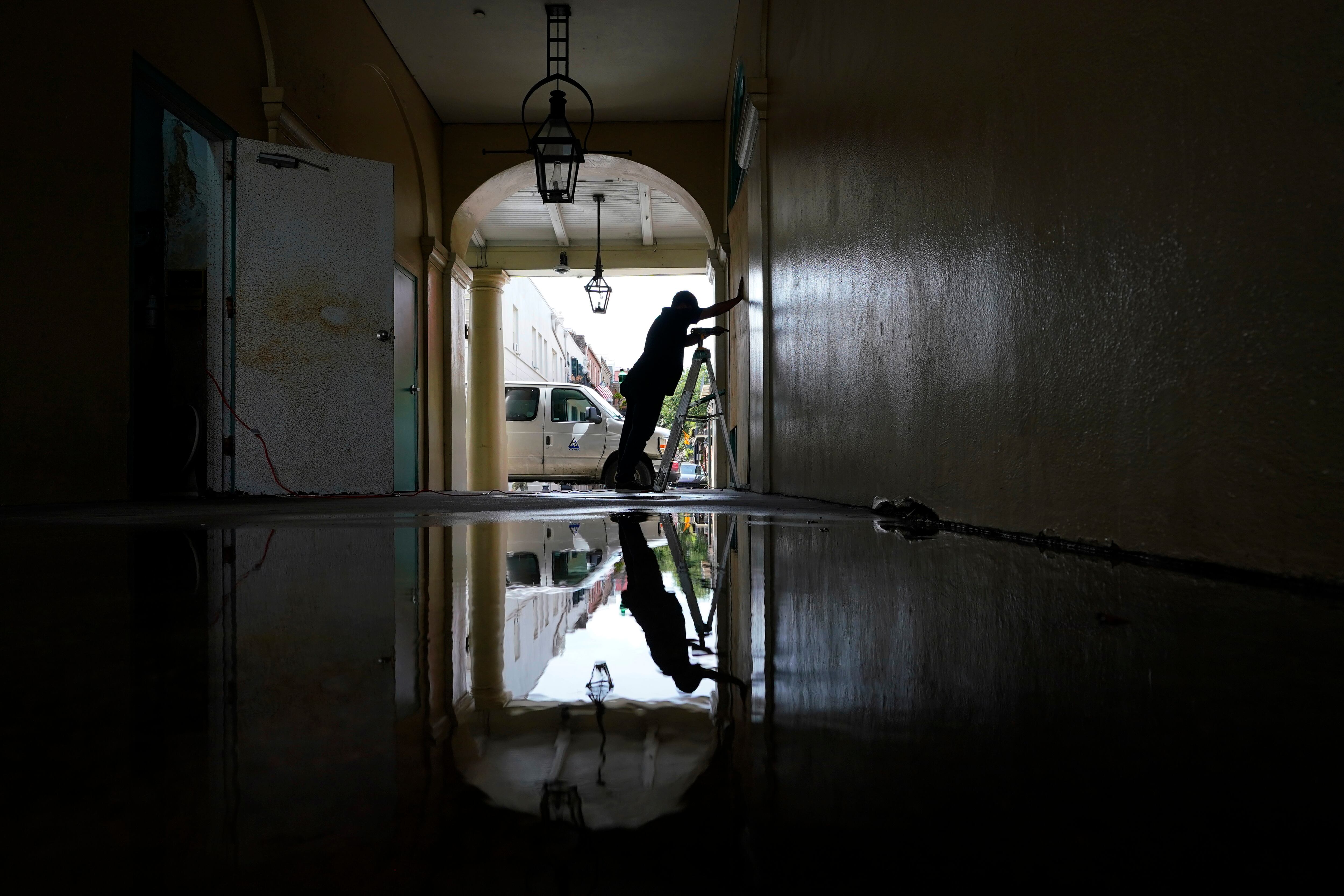 Un trabajador coloca tableros de madero en ventanas y puertas de un negocio en el Barrio Francés de Nueva Orleans. (AP Foto/Eric Gay)