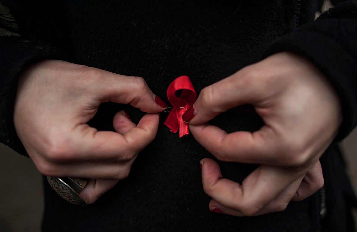 Una mujer ajusta un listón rojo, símbolo de la lucha contra el sida, durante una demostración en Pamplona, España. (AP)