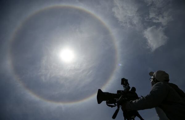 Un camarógrafo mira una aureola en la atmósfera que rodea el sol en Nueva Jersey, Estados Unidos. (AP)