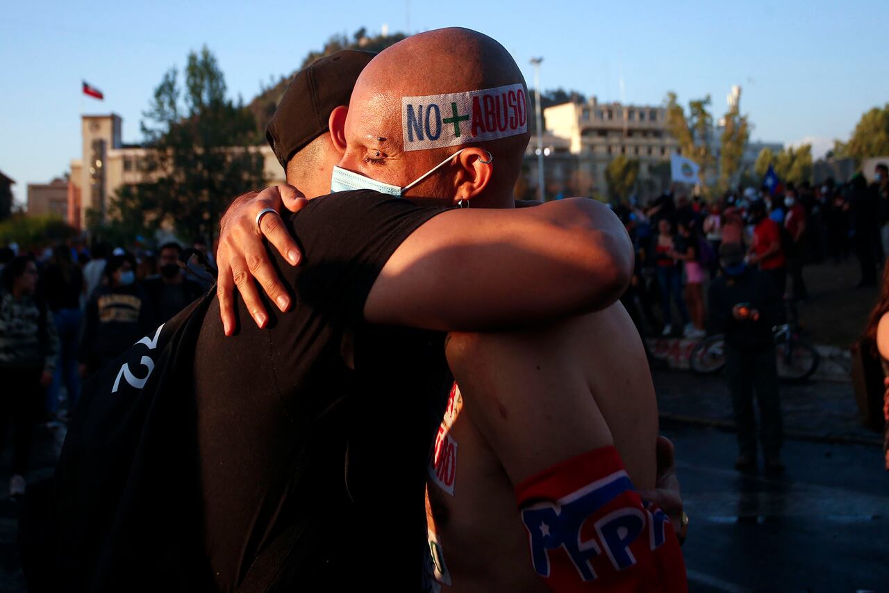 Dos hombres, uno con un letreo en la cabeza que dice "No más abusos", se abrazan el día en que los chilenos votaron en un referéndum para decidir si el país debería reemplazar su constitución de 40. Foto: AP / Luis Hidalgo.