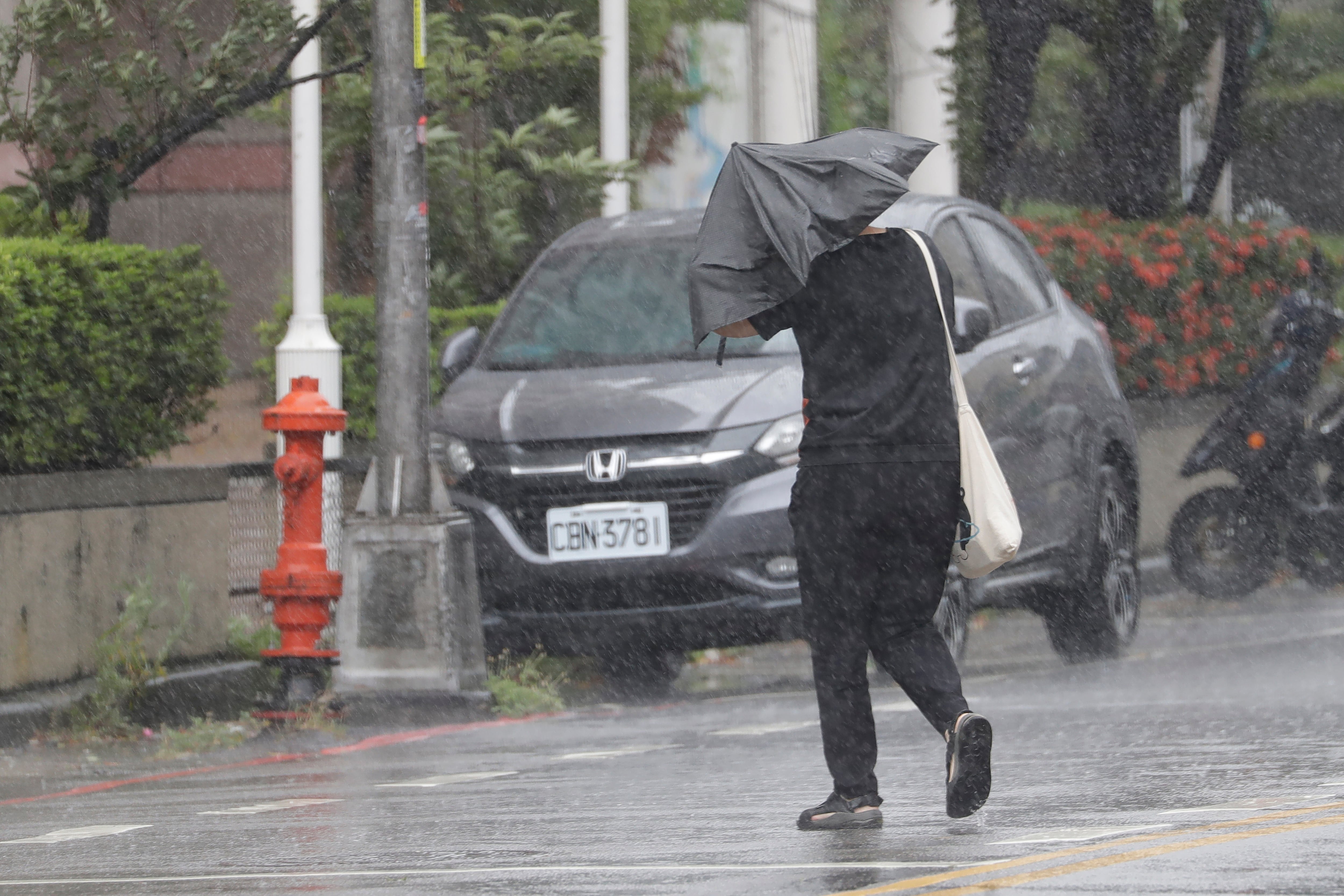 Una persona camina bajo la lluvia provocada por el tifón Bavi en Taichung, Taiwán.