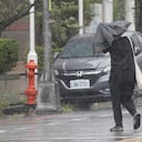 Una persona camina bajo la lluvia provocada por el tifón Bavi en Taichung, Taiwán.