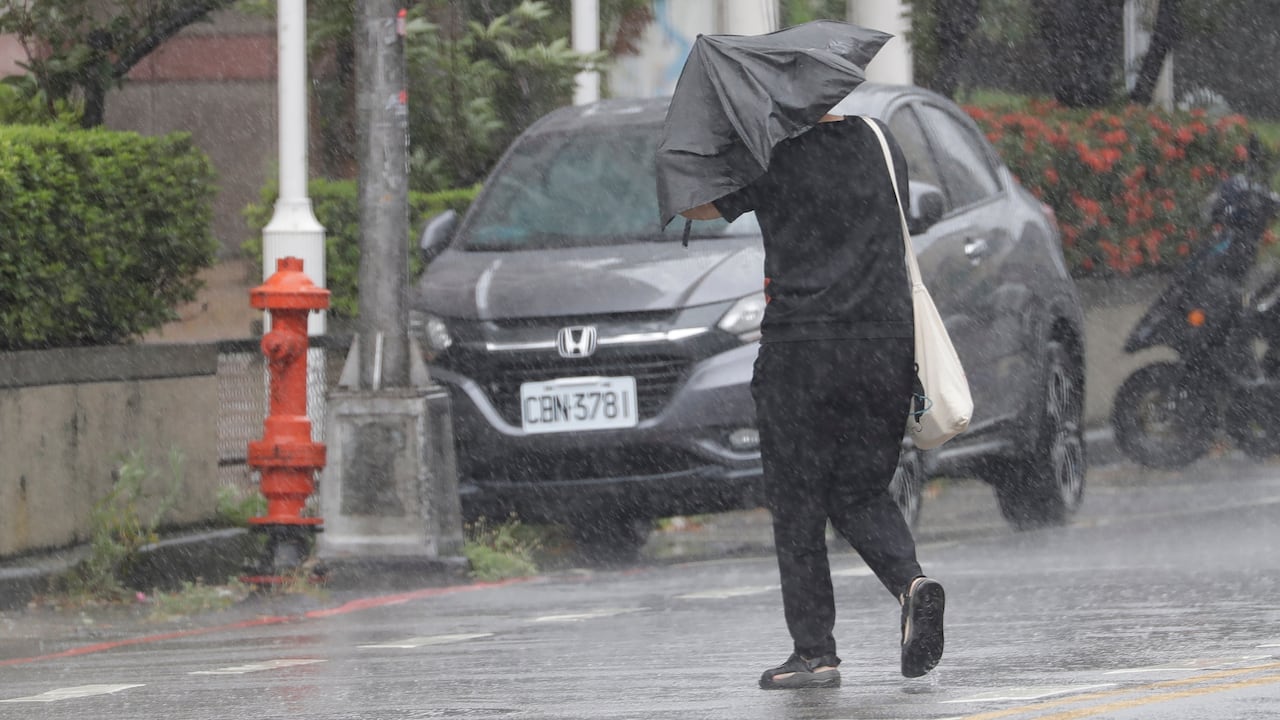Una persona camina bajo la lluvia provocada por el tifón Bavi en Taichung, Taiwán.