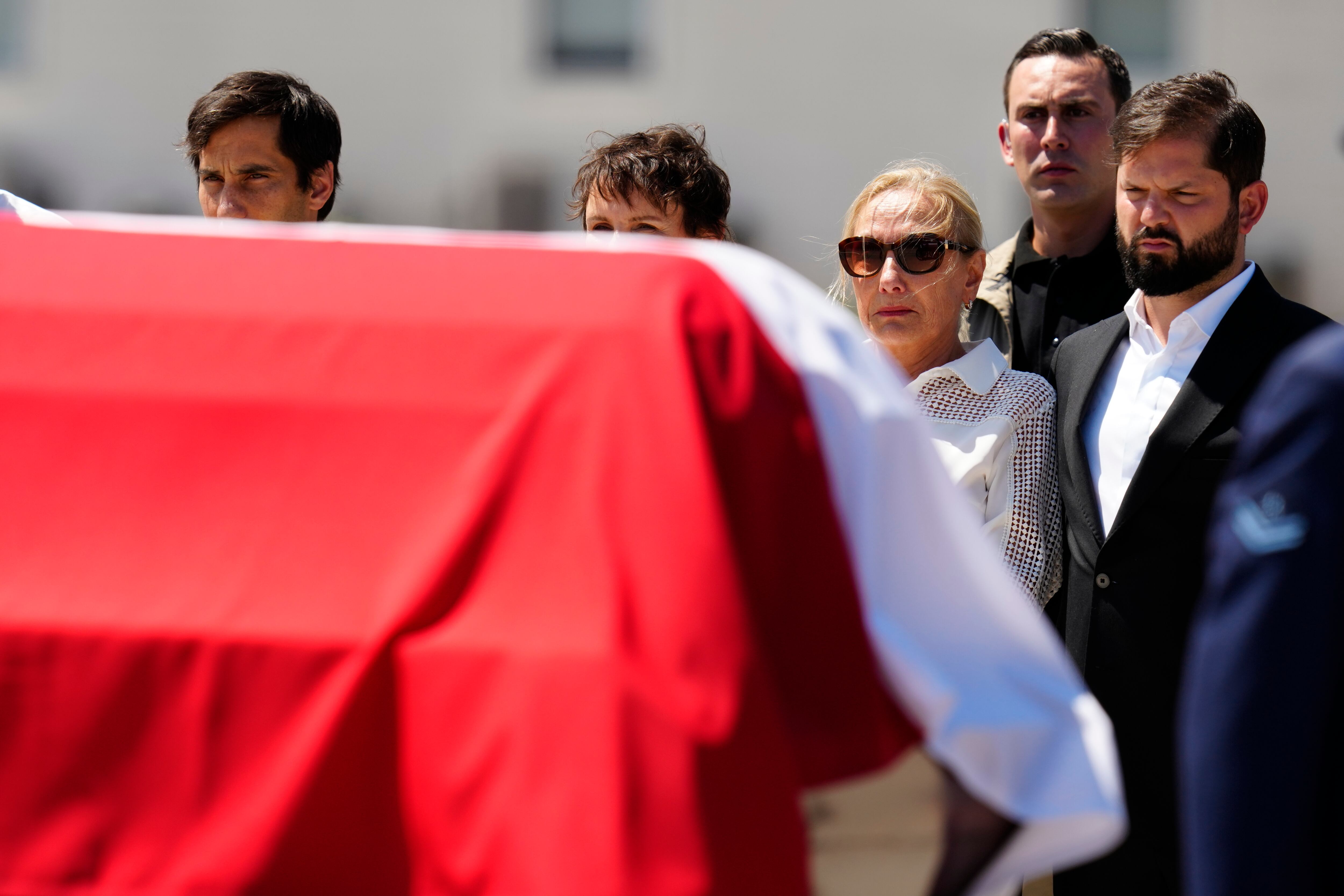 Cecilia Morel, viuda del expresidente chileno Sebastián Piñera, y el presidente chileno Gabriel Boric, a la derecha, junto al ataúd de Piñera después de su llegada al aeropuerto de Santiago, Chile, el miércoles 7 de febrero de 2024.