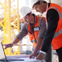 Trabajadores de la construcción que usan una computadora portátil en el sitio de construcción