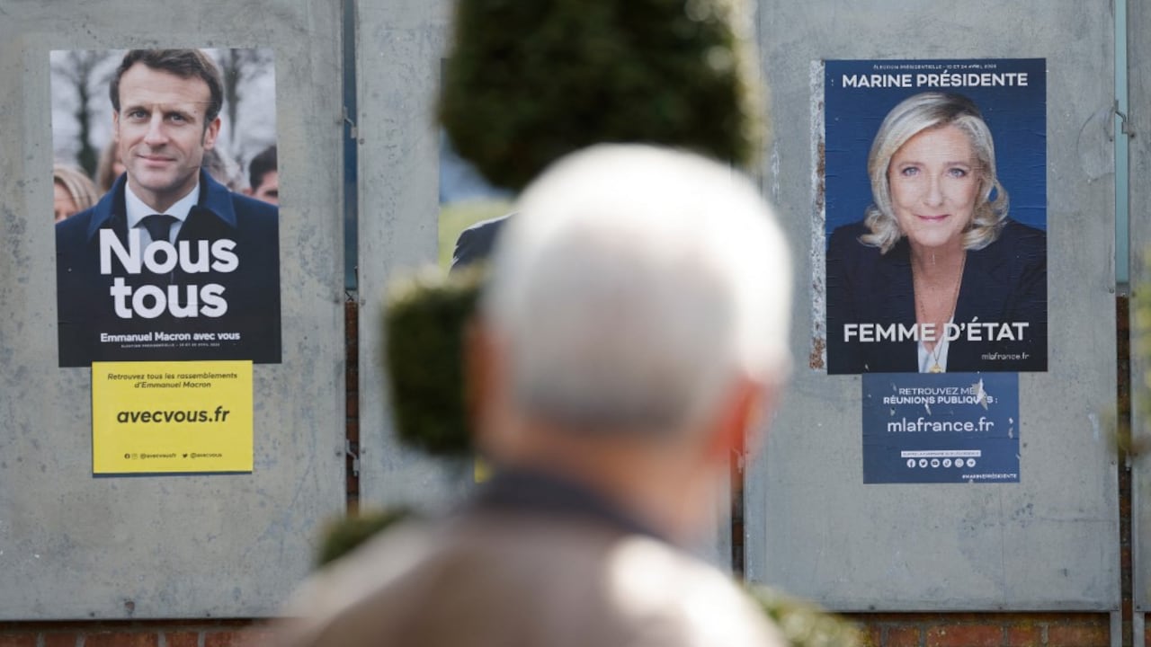 Un hombre camina junto a carteles de campaña de los candidatos presidenciales franceses, el actual presidente Emmanuel Macron (L) y la candidata presidencial del partido de extrema derecha francés Rassemblement National (RN) Marine Le Pen en Denain, el 11 de abril de 2022. Emmanuel Macron obtuvo el 27,85 por ciento de los votos. en la primera ronda de las elecciones presidenciales de Francia, mientras que la veterana de extrema derecha Marine Le Pen obtuvo un 23,15 por ciento, según los resultados finales del Ministerio del Interior el lunes.(Foto por Ludovic MARIN / AFP)