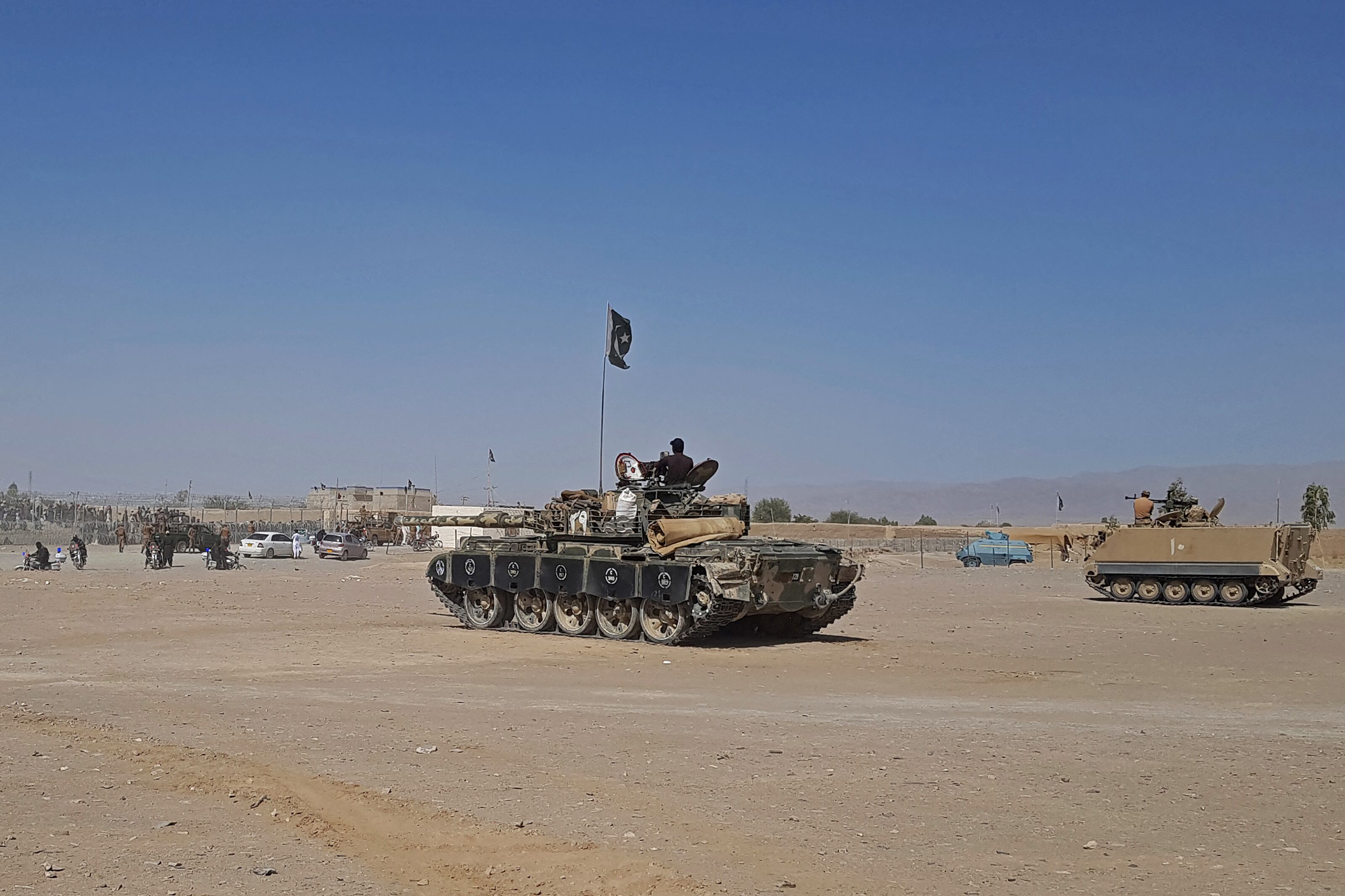 El personal de seguridad paquistaní se sienta en un tanque militar (C) y en un vehículo blindado (R) mientras vigilan cerca del punto fronterizo entre Pakistán y Afganistán en Chaman el 12 de agosto de 2021. (Foto por - / AFP)
