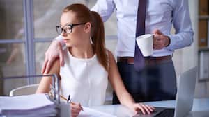 Empresario abrazando a su linda secretaria en el trabajo, ella mirando su mano