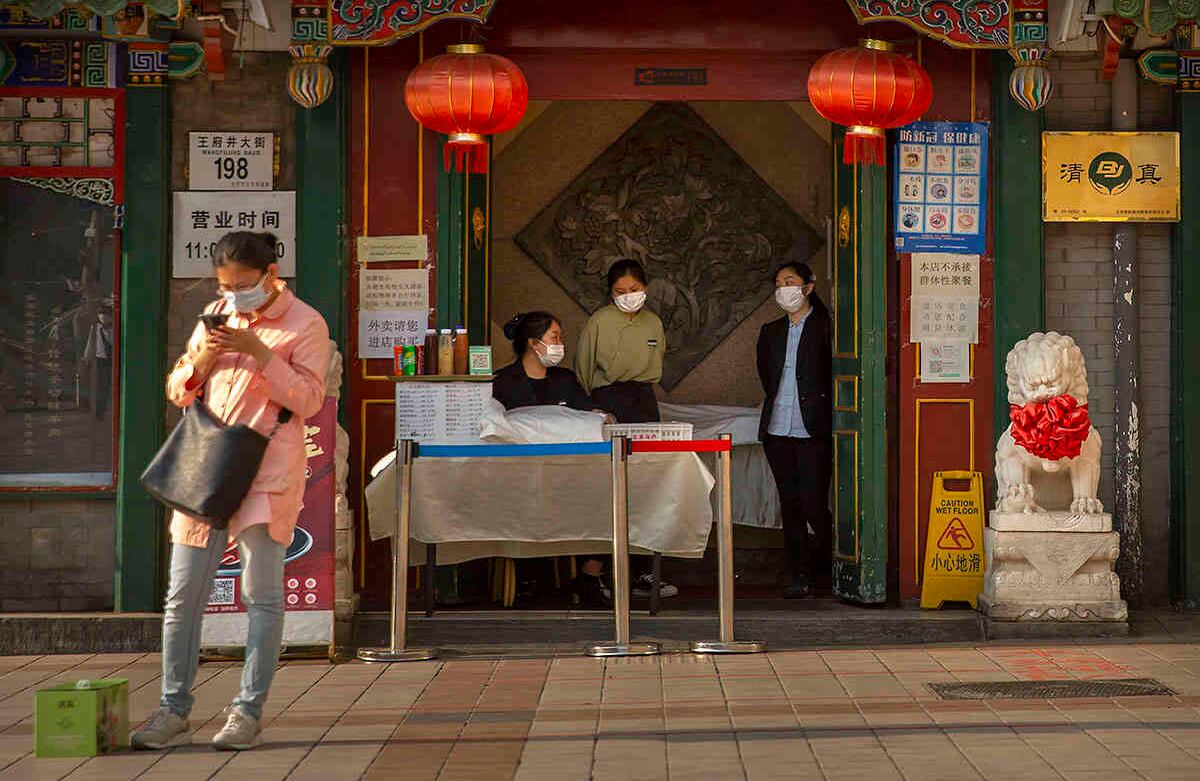 Empleados con tapabocas esperan a los clientes en la entrada de un restaurante en Beijing. Andy Wong / AP