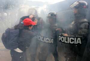 Una mujer se enfrenta al escuadrón antimotines de la policía metropolitana de Bogotá en medio de gases lacrimógenos, durante las protestas realizadas por un grupo de desplazados en el parque de la 93. Los manifestantes se quejaron de que el gobierno no ha cumplido sus promesas, las que realizó en julio de este año en materia de vivienda y apoyo económico