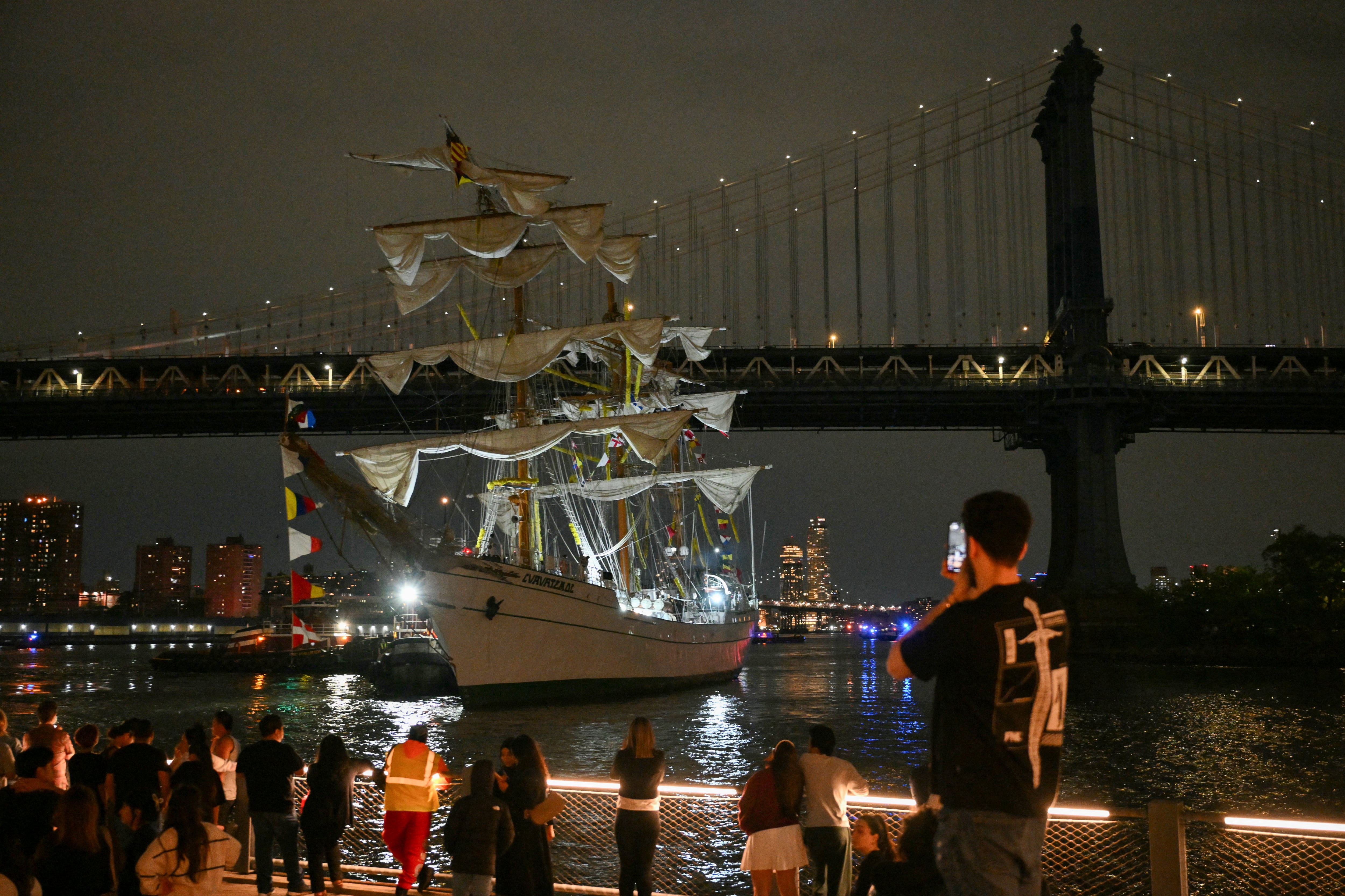 Personas observan cómo un buque escuela de la Armada de México es retirado tras estrellarse contra el Puente de Brooklyn en Nueva York, el 17 de mayo de 2025.