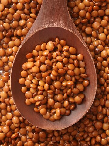 Top view of wooden spoon full of soaked lentils