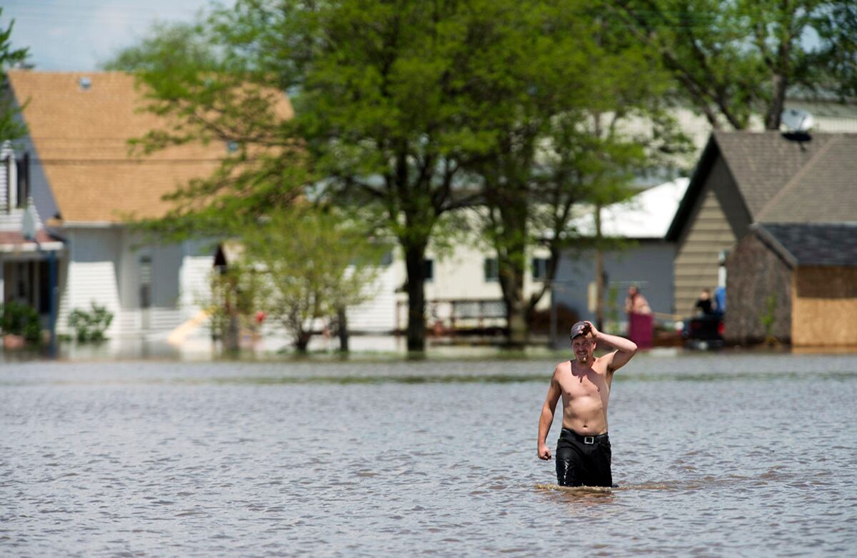 Un hombre camina entre el agua para conseguir suministros que le dará un amigo suyo. La noche anterior, las tormentas generaron tornados e inundaciones en Nebraska, Estados Unidos. (Matt Ryerson/via AP)