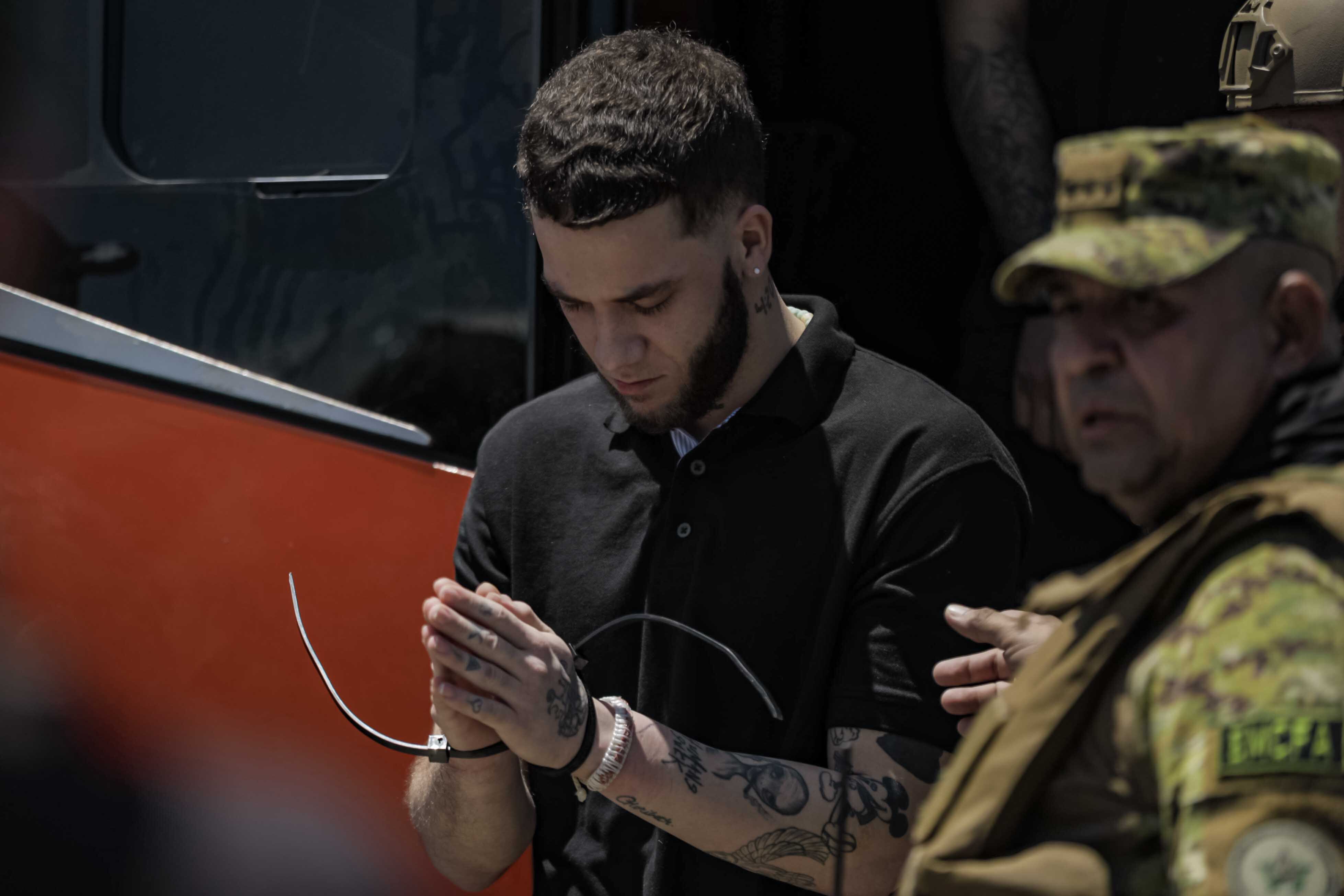 Uno de los presos venezolanos en El Salvador baja de un vehículo para ser trasladado al avión con destino a Caracas