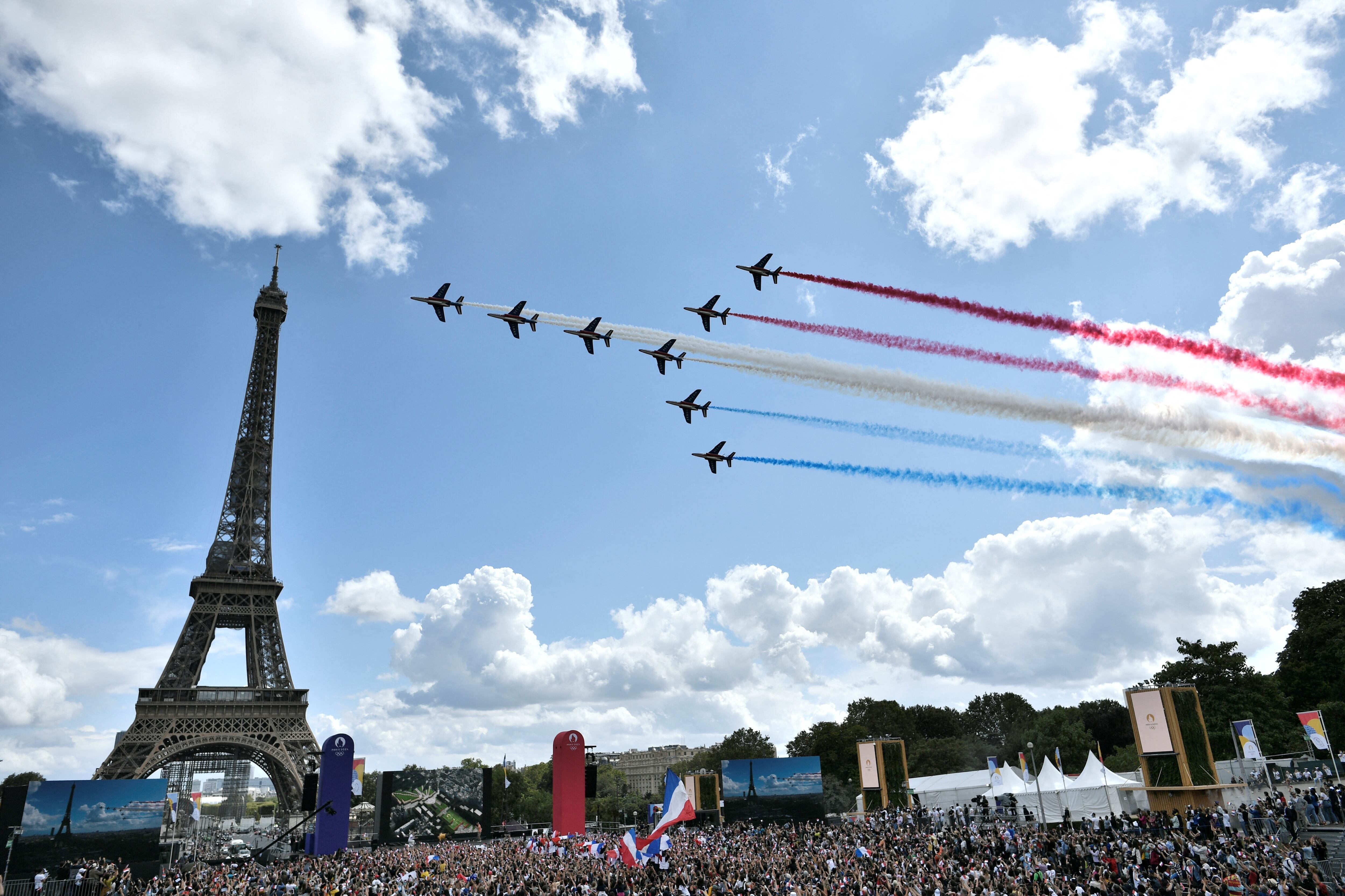 La patrulla aérea francesa 'Patrouille de France' sobrevuela la aldea de fans de El Trocadero frente a la Torre Eiffel, en París, el 8 de agosto de 2021 tras la transmisión de la ceremonia de clausura de los Juegos Olímpicos de Tokio 2020. (Foto de STEPHANE DE SAKUTIN / AFP)