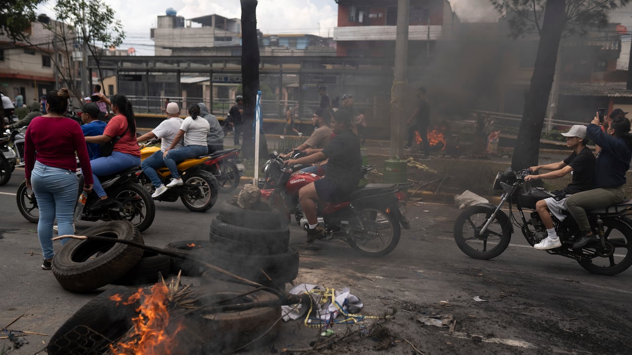 Manifestantes pasan en motocicletas frente a una barricada durante un paro nacional, en la Ciudad de Guatemala, el martes 10 de octubre de 2023. La gente protesta para apoyar al presidente electo Bernardo Arévalo después de que el tribunal más alto de Guatemala confirmó una medida de los fiscales para suspender su partido político por presunto votante. fraude de registro.