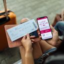 Close-up of the passport, phone, and ticket, with a bag in the distance