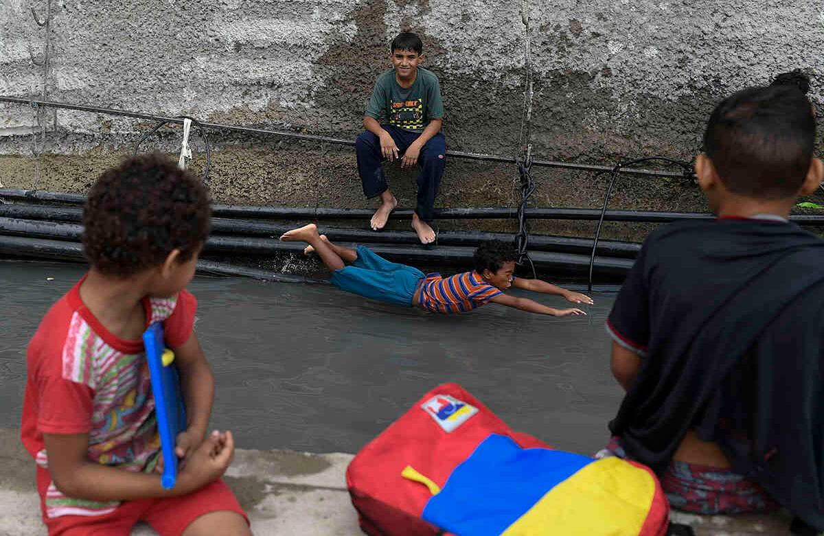 Pese a la preocupación de no tener agua potable, los niños encuentran el lado divertido al canal de agua improvisado que se hizo a las afueras del túnel. Un pequeño se desliza como si estuviera en un parque de diversiones.  Foto: Matias Delacroix /AP.
