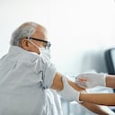 Enfermera inyectando la vacuna Covid-19 a un paciente anciano. El trabajador de la salud está examinando a un anciano en el hospital. Ella está usando una máscara facial durante COVID-19.