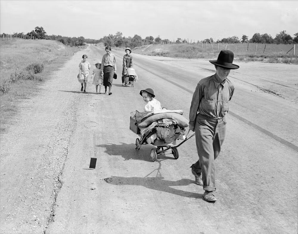 Imagen de Dorothea Lange en la que retrata a una familia con cinco niños caminando por la carretera, con destino a Krebs, Oklahoma (Estados Unidos). En 1936, el padre cultivaba tierras a cambio de una tercera y cuarta parte de la cosecha. Enfermó de neumonía y perdió la granja. No pudo conseguir trabajo en la Administración y le denegaron la ayuda del condado en el que había residido durante quince años debido a su residencia temporal en otro condado tras su enfermedad. Library of Congress's Prints and Photographs division
