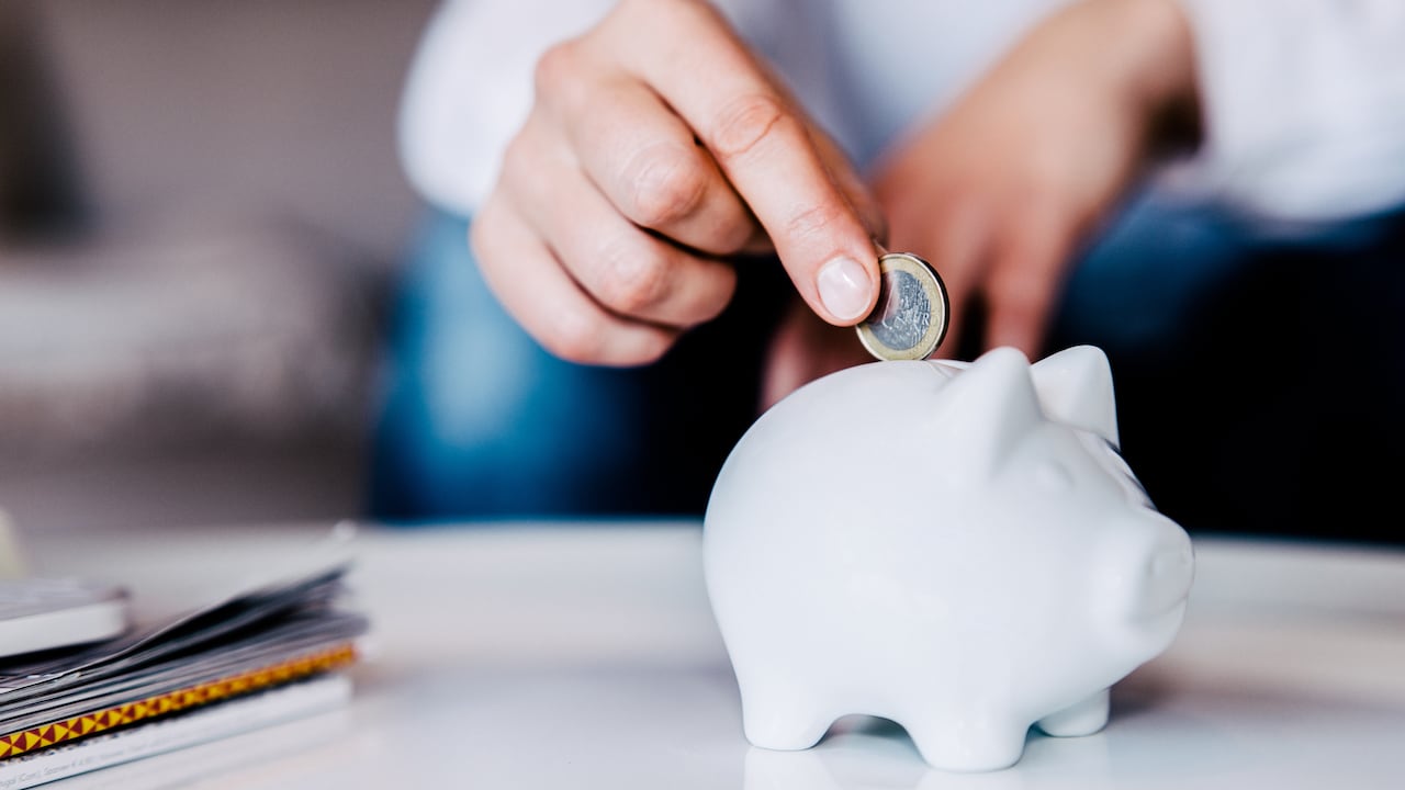 Putting a coin in a white piggy bank at home.