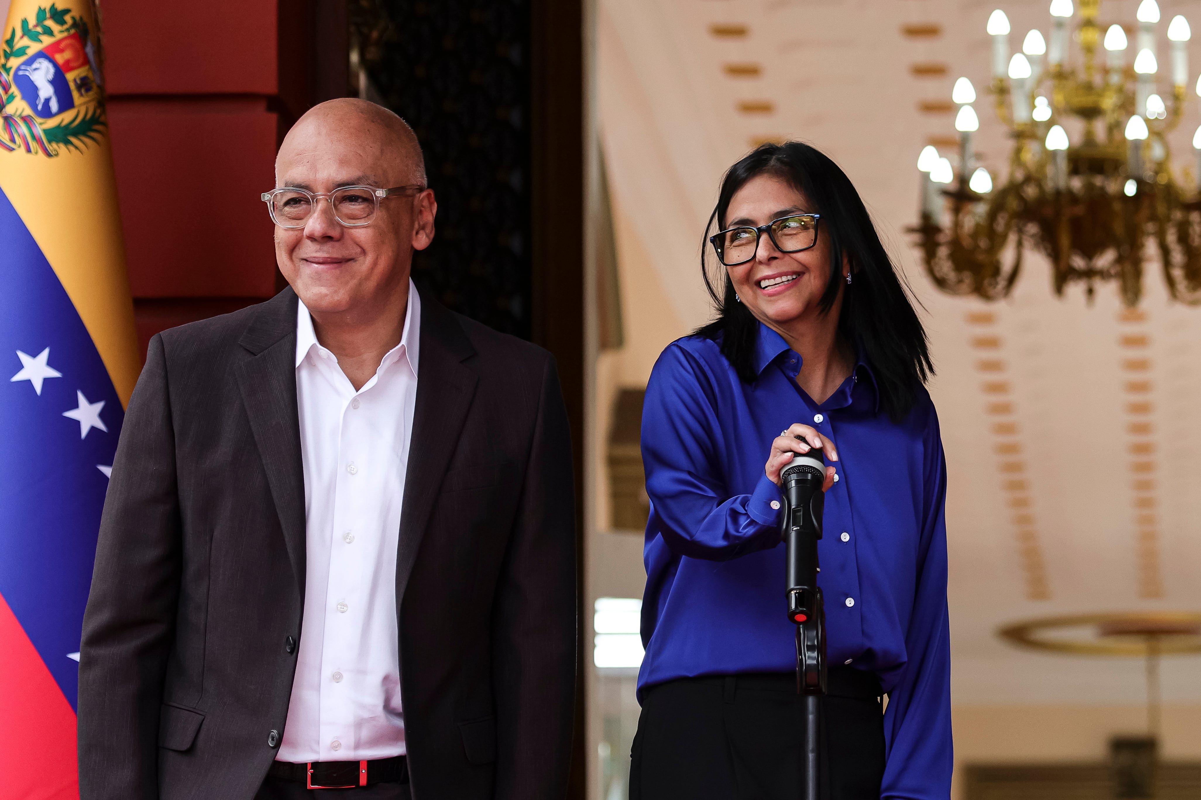 La presidenta interina de Venezuela, Delcy Rodríguez (C), sonríe junto al presidente de la Asamblea Nacional, Jorge Rodríguez (I), durante una conferencia de prensa sobre la liberación de presos en Venezuela, celebrada en el Palacio de Miraflores el 14 de enero de 2026 en Caracas, Venezuela.