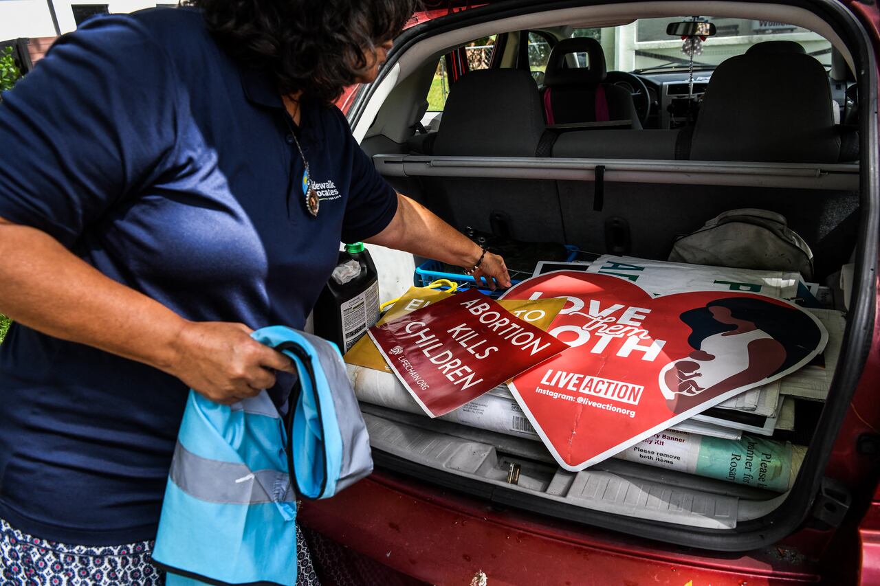 Anti-abortion activist Madelyn Ocasio takes banners and posters from her car outside of her house in Miami, Florida, on May 3, 2022. - The Supreme Court is poised to strike down the right to abortion in the US, according to a leaked draft of a majority opinion that would shred nearly 50 years of constitutional protections. The draft, obtained by Politico, was written by Justice Samuel Alito, and has been circulated inside the conservative-dominated court, the news outlet reported. Politico stressed that the document it obtained is a draft and opinions could change. The court is expected to issue a decision by June. The draft opinion calls the landmark 1973 Roe v Wade decision "egregiously wrong from the start." (Photo by CHANDAN KHANNA / AFP)