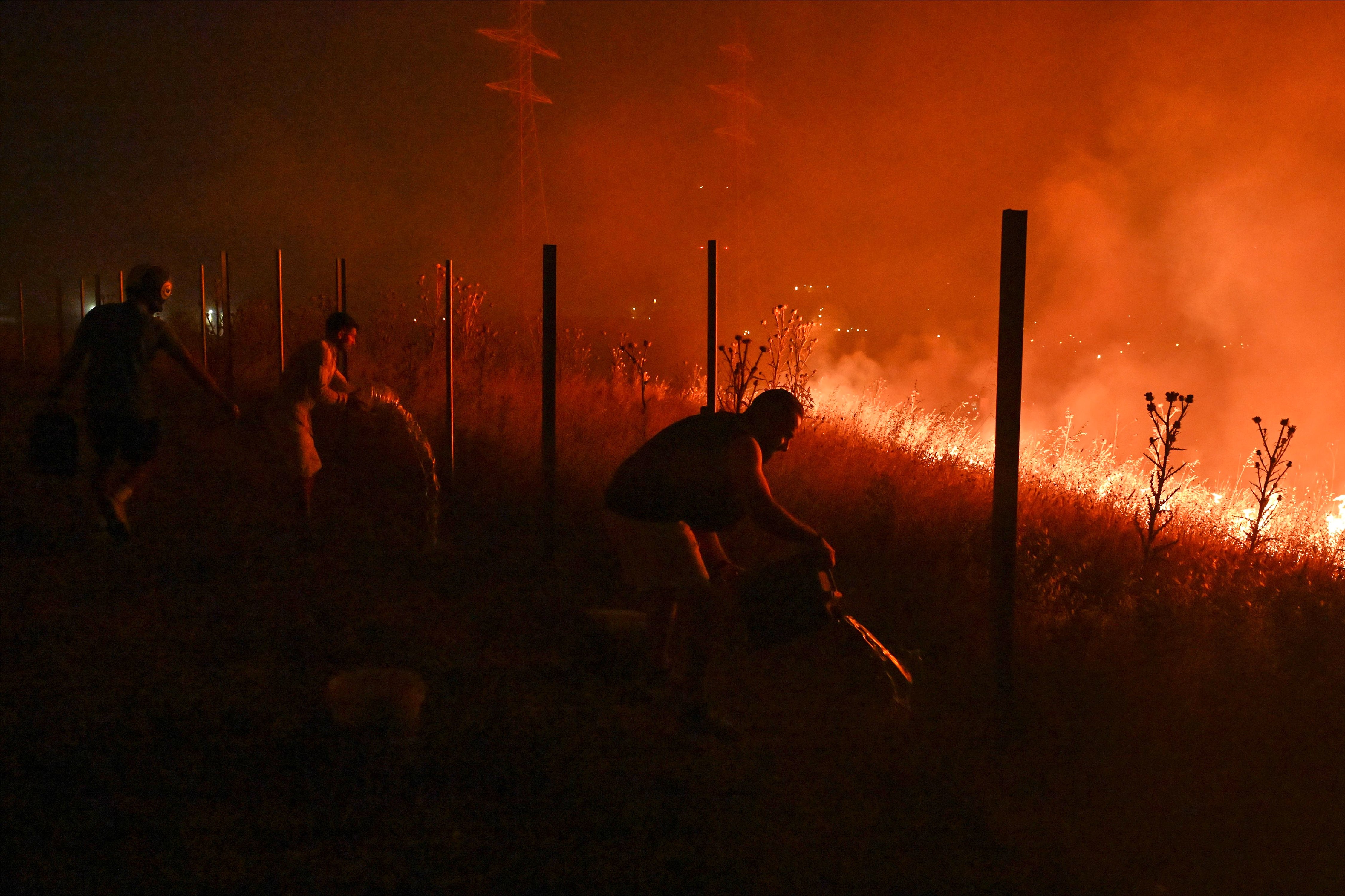 Residentes locales intentan extinguir un incendio forestal en las afueras de la ciudad de Salónica, en el norte de Grecia.