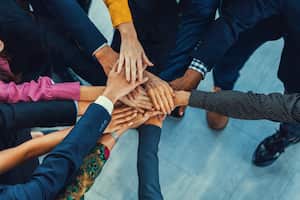 A group of diversity people putting their hands together. Showing unity teamwork and friendship. Close up top view of young business man and business woman joining as a team. Intellectual.