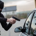 Terrorista o ladrón de autos apuntando con un arma al conductor - dueño del auto