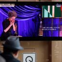 People watch live broadcast on TV showing South Korean actress Yuh-Jung Youn receiving the Oscar for best supporting actress for her performance in “Minari,” at Seoul Railway Station in Seoul, South Korea, Monday, April 26, 2021. The Korean letters read: "93rd Academy Awards" and "Yuh-Jung Youn receives the award for best actress in a supporting role." (AP Photo/Lee Jin-man)