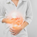 Manos de mujer tocando el vientre y el estómago dolorosos que sufren de gastritis crónica sobre fondo blanco. concepto de salud.