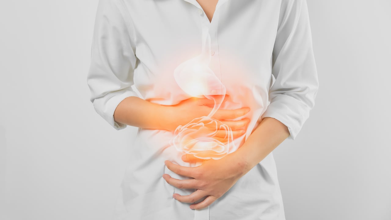 Manos de mujer tocando el vientre y el estómago dolorosos que sufren de gastritis crónica sobre fondo blanco. concepto de salud.