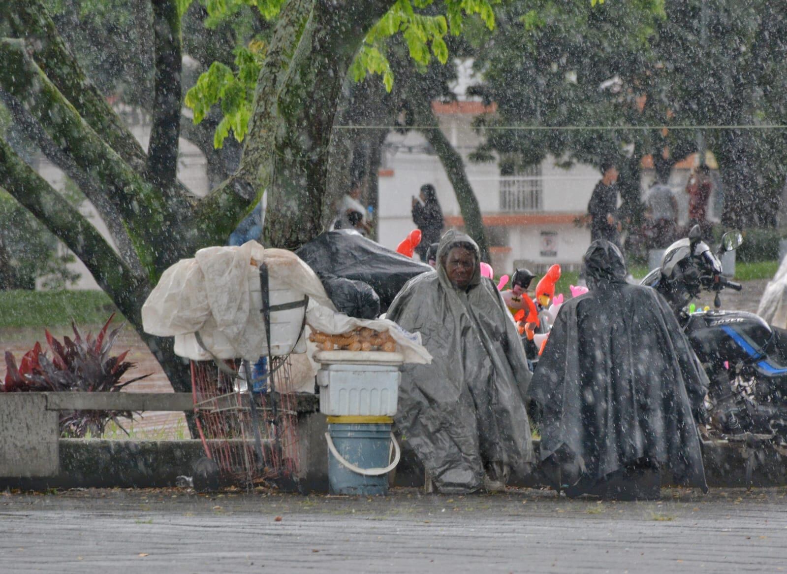 Vendedores ambulantes tuvieron que ponerse capas para protegerse del agua de las lluvias en el sur de Cali.