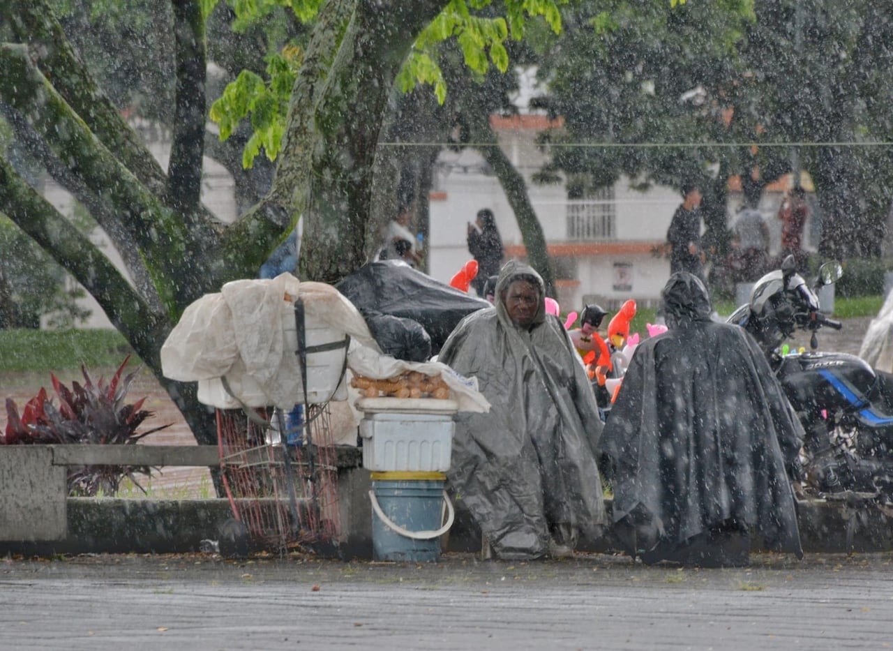 Vendedores ambulantes tuvieron que ponerse capas para protegerse del agua de las lluvias en el sur de Cali.