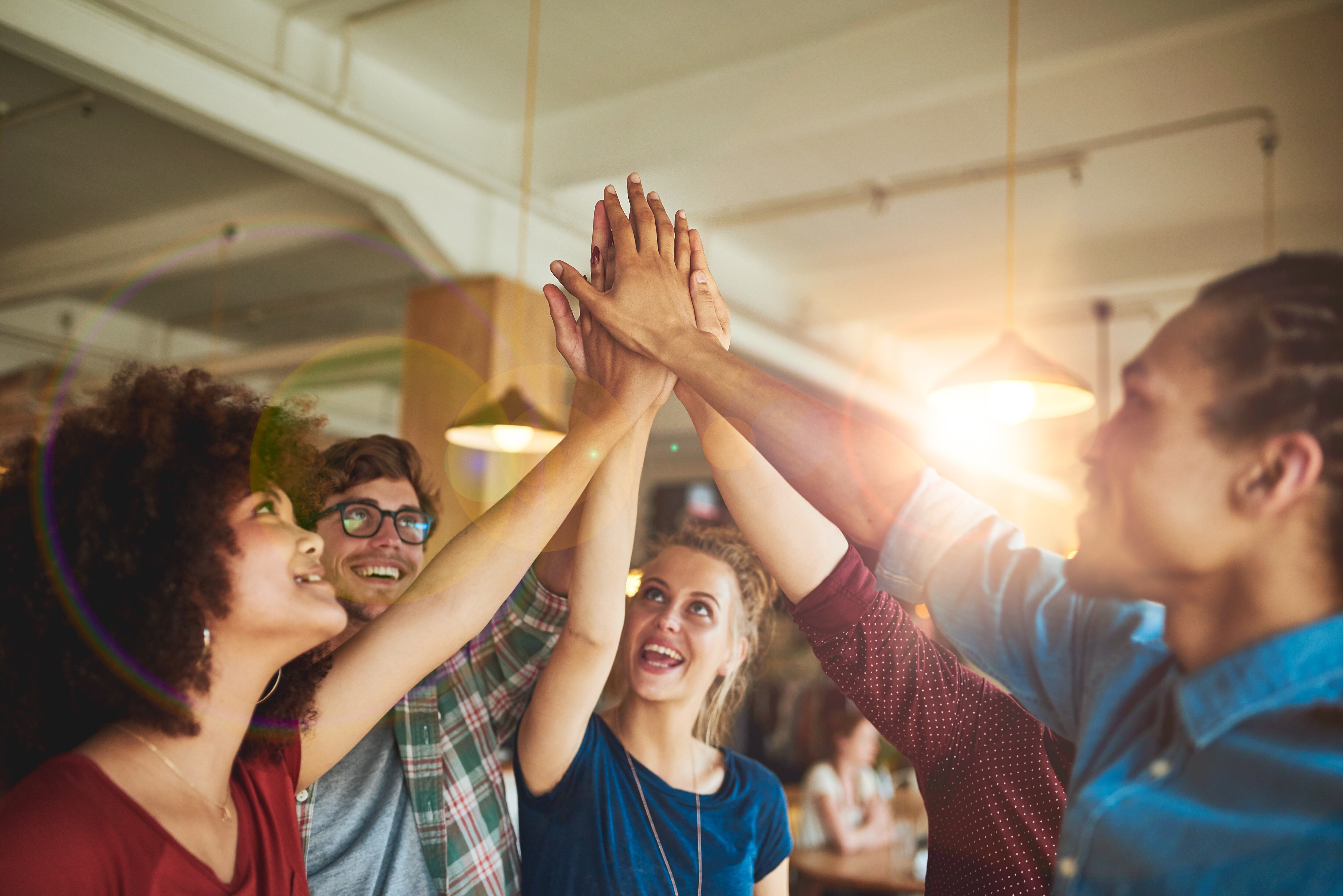 Shot of a group of friends high fiving together