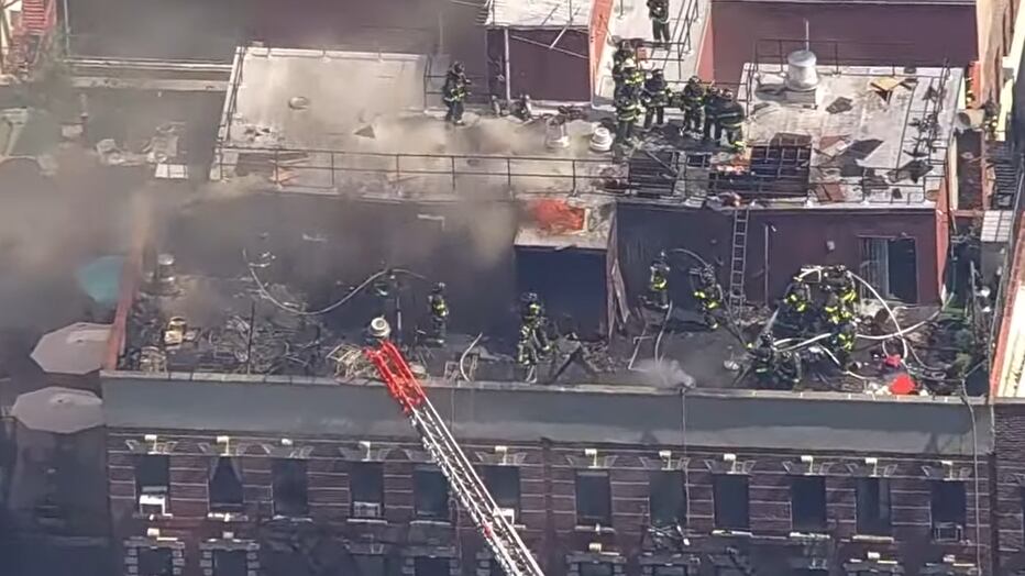 Incendio en azotea de edificio en Manhattan con gran despliegue de bomberos y densa nube de humo.